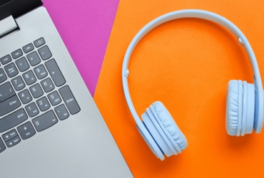 laptop and headphones on an orange and pink background